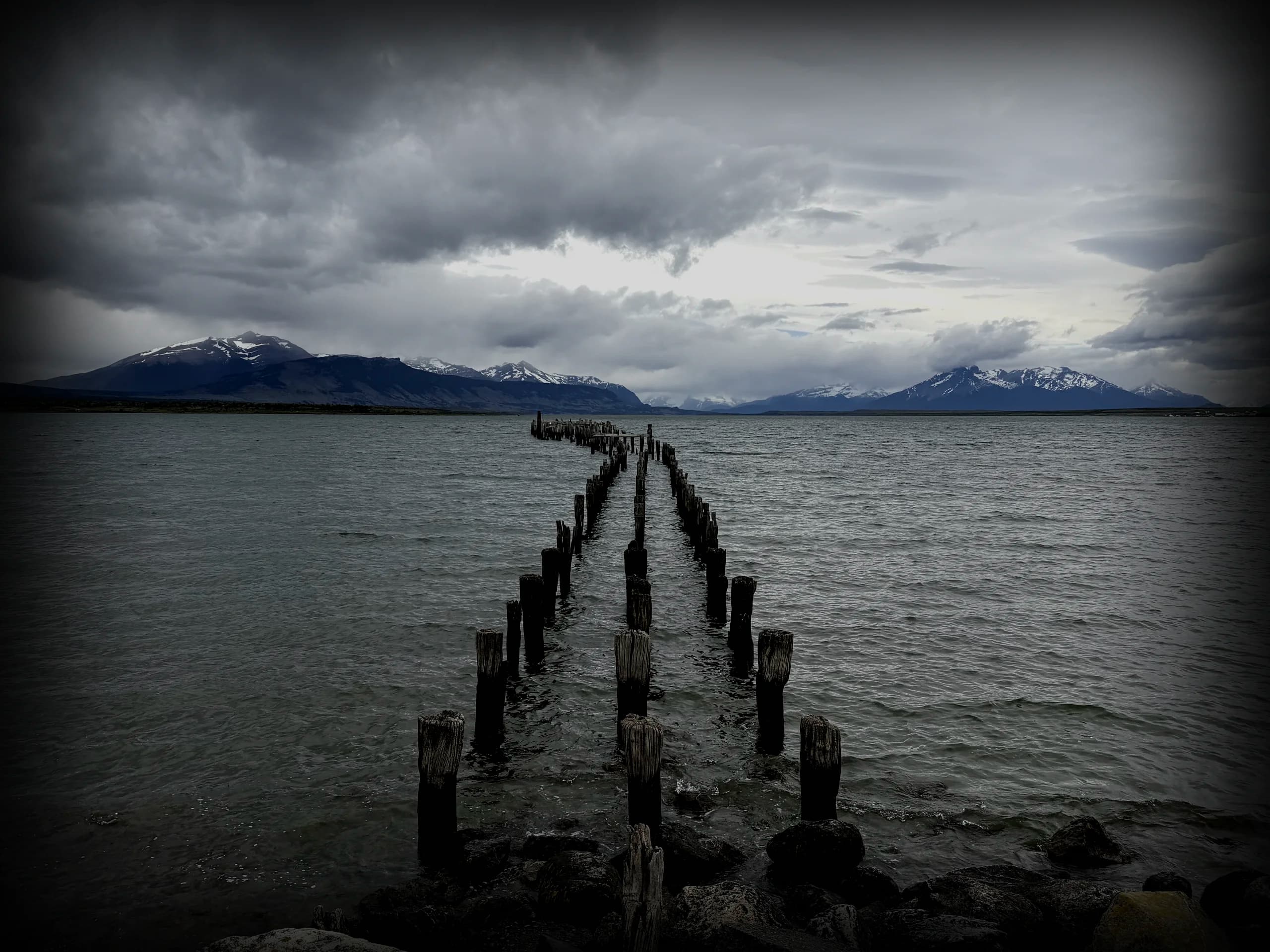 Wooden pier extending into Patagonian waters toward distant mountains